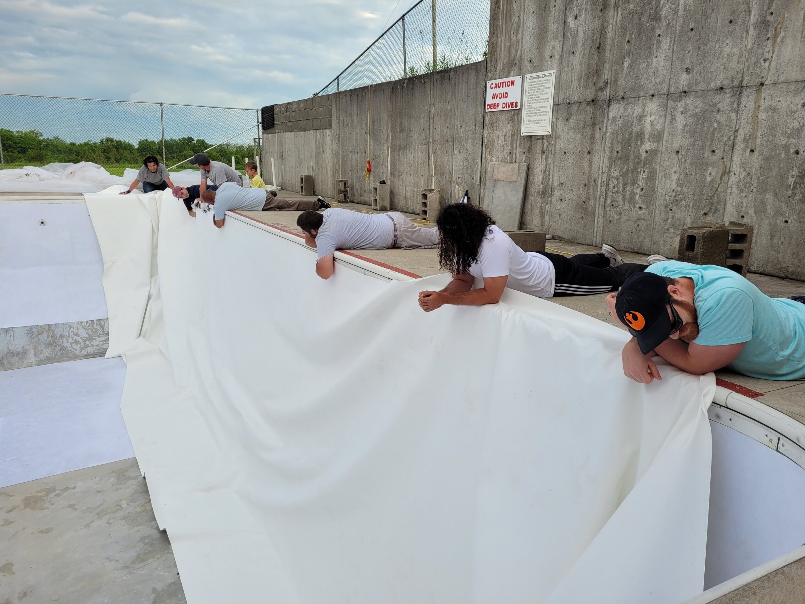 The installers putting the PVC membrane on the pool wall